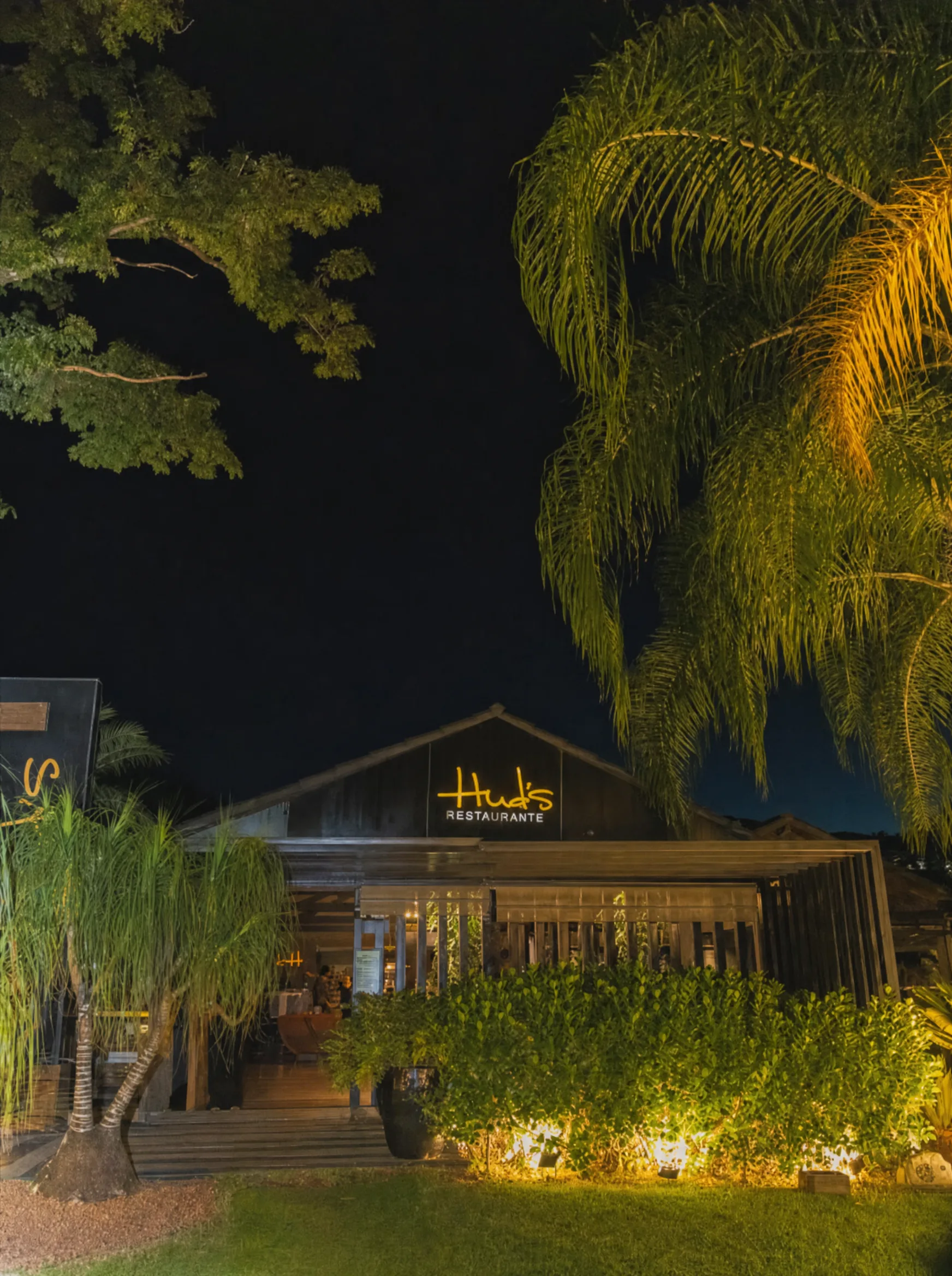 Fachada do Hud's à noite com letreiro neon